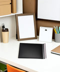 50 Pack Black Bubble Mailers For Shipping Clothes And Small Packages on a desk surrounded by office supplies.