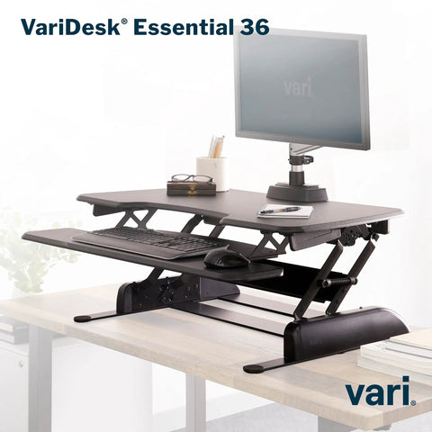 Two Tier Standing Desk Converter With Dual Handle Lift For Monitors And Accessories, 36 Inch Wide Sit Stand Riser, shown in an office