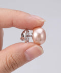 Close-up of a hand holding a no sew faux pearl brooch pin from the 25Pcs No Sew Faux Pearl Brooch Pins Detachable Sweater Clips Reusable Shirt Fasteners.