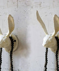 Sturdy Cast Iron Rabbit Wall Hooks Featuring Rustic Antique White Vibes With Zero Hassle Setup Heavy Duty Mounting Hardware Included For Top Tier Home Organization That Truly Cuts Through Clutter. Rabbit wall hook with beads on antique white background.
