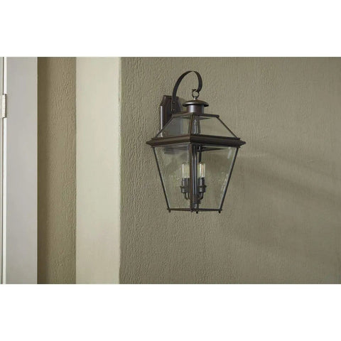 Burlington Three Light Large Wall Lantern with clear beveled glass in antique bronze, mounted on patio wall.