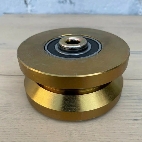 Badass 4 Inch Solid Gate Roller Wheel With Dual Bearing V Groove, Zinc Plated Gold Finish. Side view showing dual bearing.