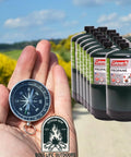 Hand holding compass with 12 Pack 16 Ounce Propane Cylinders For Camping And Outdoor Cooking Great For Grilling On The Go Durable Steel Construction Pre Filled 1 Pound Tanks For Camp Stoves Tabletop Grills Torches Portable Propane Appliances Made In The US Fits Adapters Green in background