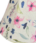 Floral fabric detail on a lampshade with pink and purple flowers on a beige background.