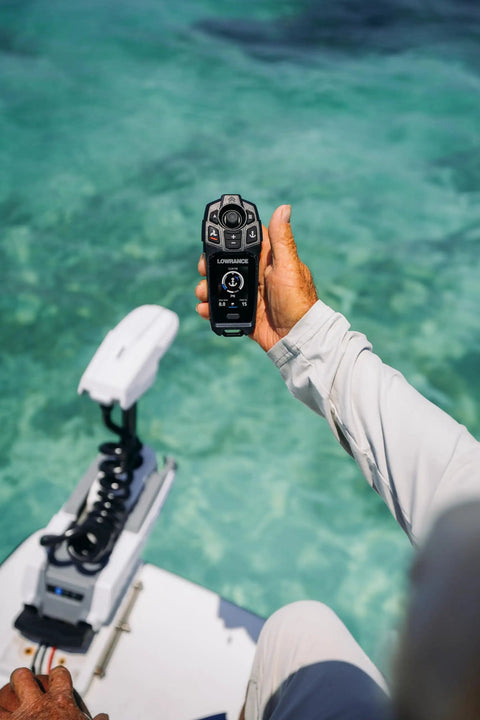 Recon Saltwater 72 Inch Trolling Motor with FreeSteer Joystick Remote in hand over clear water, showcasing intuitive controls.