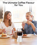 Two women enjoying coffee with Stovetop Moka Pot For 9 Cups Espresso Maker 15oz Italian Coffee Clear Glass And Stainless Steel Base on table.