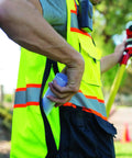 Close-up of a man wearing a lime vest, retrieving a rolled document from a pocket of the Mens Premium Surveyor Vest Class 2 Hi Vis Safety Vest.