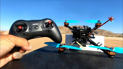 R8FM 8 Channel 2.4GHz Micro RC Receiver with SBUS PPM Output shown with controller and racing drone outdoors