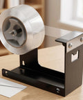 Heavy Duty Desktop Tape Dispenser With Solid Steel Base And Precision Serrated Blade For Straight Up Clean Cuts On Packing Boxes And Office Supplies No Sweat Desk Setup on wooden desk.