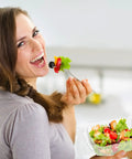 Smiling person holding a salad in a clear plastic hinged takeout clamshell container, showcasing its easy-to-use design.