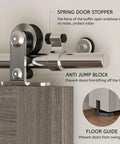 Close-up of stainless steel sliding barn door hardware kit with spring door stopper and anti-jump block installation details.