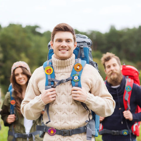 People wearing I Love Camp Pins For Kids 60 Pcs Outdoor Camping Button Accessories on backpacks in a camping setting