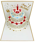 3D pop-up birthday card by Akeydeco: white tiered cake with red candle, blue floral garlands; includes envelopes.