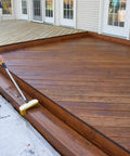 Person applying Heavy Duty Wood Stain And Sealer In One For Decks, 5 Gallon Semi Transparent Waterproof Coating In Light Walnut.