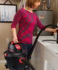 Person using Heavy-Duty 6 Gallon Wet Dry Vacuum With 3 Peak HP Power near washing machine in a utility room.