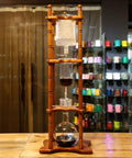 Slick Cold Brew Coffee Tower Featuring A Reliable Ice Drip System For Bold Flavor Kick Holds A Humongous 3000ML Glass Jar Settled On A Raw Brown Wood Stand Perfect For Patio Hangouts Or Friday Night House Vibes