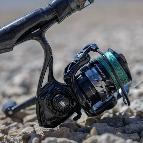 Close-up of Lite II Spinning Reel For Freshwater Fishing, Ultra Lightweight Graphite Body, 14.3 Lb Max Drag, on rocky ground.