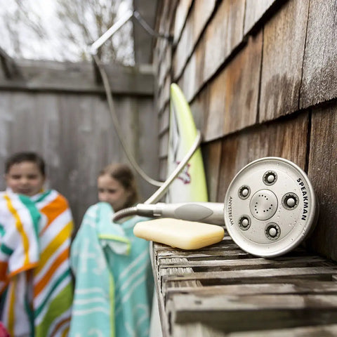 Caspian 2.5 GPM Anystream Hand Shower With 3 Settings, brushed nickel finish, displayed on outdoor shelf in a rustic setting