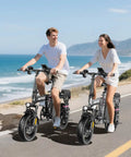 Two people riding 1200W Folding Electric Bike For Adults And Teens, 25 MPH Peak Power, 48V 10Ah Battery, 45 Mile Range by the coast
