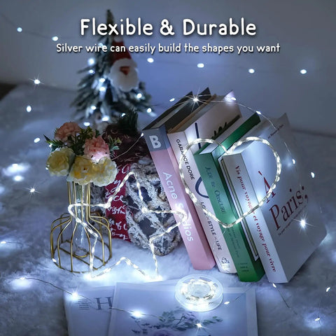 Two Pack Of 33 Feet Solar String Lights With 100 LEDs Each, wrapped around books, demonstrating flexibility and warm white glow
