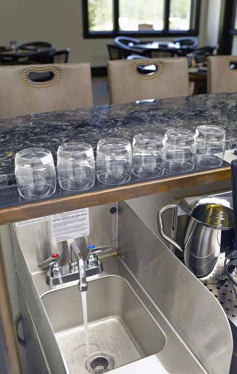 Brass Deck Mount Workboard Mixing Faucet with Six Inch Swing Nozzle operating at a commercial sink, water flowing.