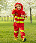 Child in red firefighter costume with toy water squirt gun, outdoors in a park, representing fun summer play.