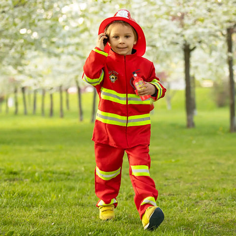 Child in red firefighter costume with toy water squirt gun, outdoors in a park, representing fun summer play.