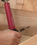 Drive90Plus Right Angle Drill Attachment in use for drilling in tight wooden space with Phillips driver bit and 1/4 inch hex bit compatibility.