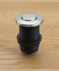 Touch Activated Garbage Disposal Air Switch Kit with metal button on wooden surface