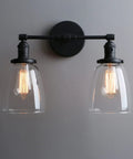 Retro Industrial 2-Light Wall Sconce Set With Dual 5.6 Inch Bell Shaped Clear Glass Lampshades, Black Finish For Bathroom Vanity