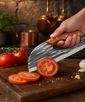 Hand Forged Chef Knife And Cleaver Set With Leather Sheath slicing tomato on wooden board, sharp kitchen tool for everyday cooking.