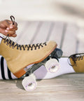 Person tying laces on brown roller skate with Light Up Roller Skate Wheels With Bearings For Quad And Inline Skates LED Indoor