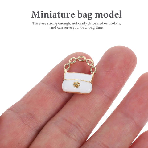 Close-up of a white miniature purse with gold chain from the Three Pack Mini Handbag Set For Dollhouse Decor And DIY Jewelry Charms.