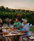 Group enjoying a meal outdoors with Premium Weatherproof Wood Stain With Semi Gloss Walnut Finish applied on tables.
