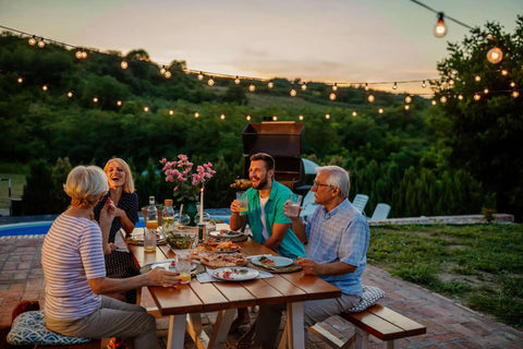 Group enjoying a meal outdoors with Premium Weatherproof Wood Stain With Semi Gloss Walnut Finish applied on tables.