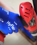 Person using a red power drill wearing HyFlex 11-618 Ultra Thin Nylon Safety Gloves For Automotive And Fabrication, Blue, Size 11 2XL