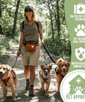 Pet Medic first aid kit bag in orange, front view of person walking three dogs on a forest trail