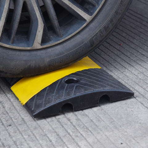 Car wheel on Heavy Duty Rubber Speed Bump 6 Foot Ramp With Integrated Cable Cover 72 Inch Long One Piece Installation Kit Built To Last