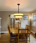 Four Light Modern Drum Chandelier With Fabric Shade hanging above wooden dining table in a farmhouse kitchen setting.