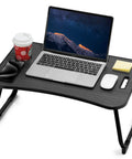 Foldable Laptop Bed Desk with cup holder, tablet slot, and handle featuring a laptop, mouse, phone, and drink on black wood surface.