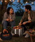 Portable 14 Inch Folding Campfire Grill With Carry Bag Stainless Steel Charcoal Grill For Camping Bonfires Picnics And Backyard Cooking Lightweight Durable Outdoor BBQ Gear being used by people at a nighttime picnic.