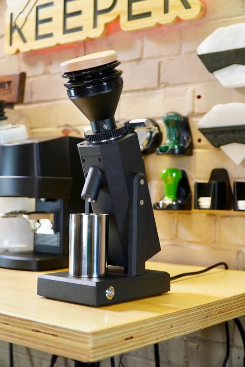 Dope Stepless Coffee Grinder Featuring 40mm Stainless Steel Conical Burrs For Pulling Consistent Espresso Shots And Brewing Smooth Daily Drips With Hella Low Retention In Matte Black on a wooden table.