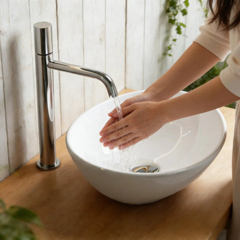 Person washing hands in NUESTRA VIDA Overhead Sink Oval Ceramic 16.1 * 13 * 5.5 IN, modern basin on wooden countertop.