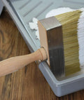 5.5 Inch Limewash Deck Brush With Wood Handle Large Paint Applicator resting in paint tray on wooden floor