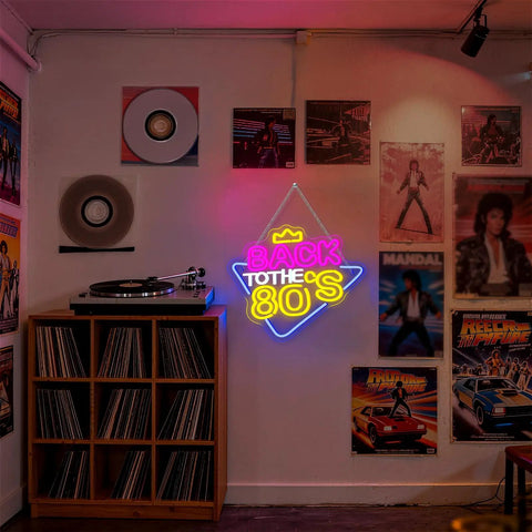 Colorful 'Back to the 80s' neon sign on dark wall near vinyl records and retro posters in music-themed room