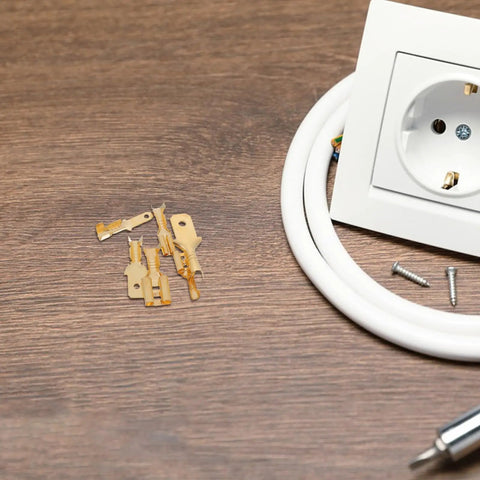 Dope 900 Piece Spade Connector Kit With Solid Copper Terminals And Secure Plastic Shells For Quick Wire Splicing Effortless Car Audio Installation And Electrical Repair Jobs That Hit Hard. Gold spade connectors beside a wall outlet on wood.