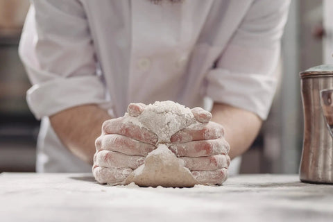 Baker kneading dough using One Gallon Baking Soda For Cooking And Baking Cleaning And More Pure Sodium Bicarbonate With Nothing Added.