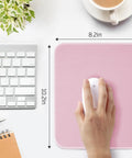 Pink Mouse Pad With Splash Proof Textured Surface And Stitched Edge For Desk, Non Slip Waterproof Rubber Base, 10.2 X 8.2 Inches shown with hand using a mouse.