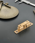 Copper Ball Catch Door Latch Set For Boats And Yachts on a black background with measuring tools