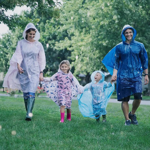 Family wearing Disposable Rain Ponchos Family Pack Eight Pack With Hood For Adults And Kids, enjoying a rainy day in the park.
